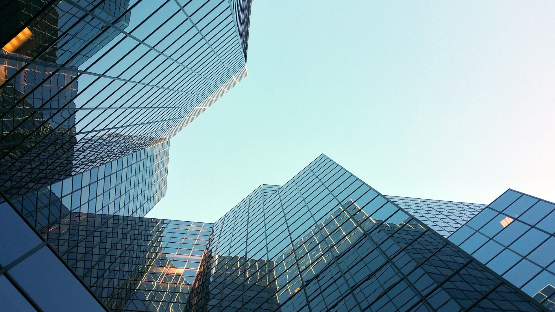 Upward view of modern glass office buildings against a clear sky.